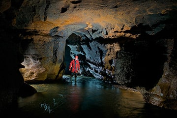 Hombre explorando una cueva con agua espeleología